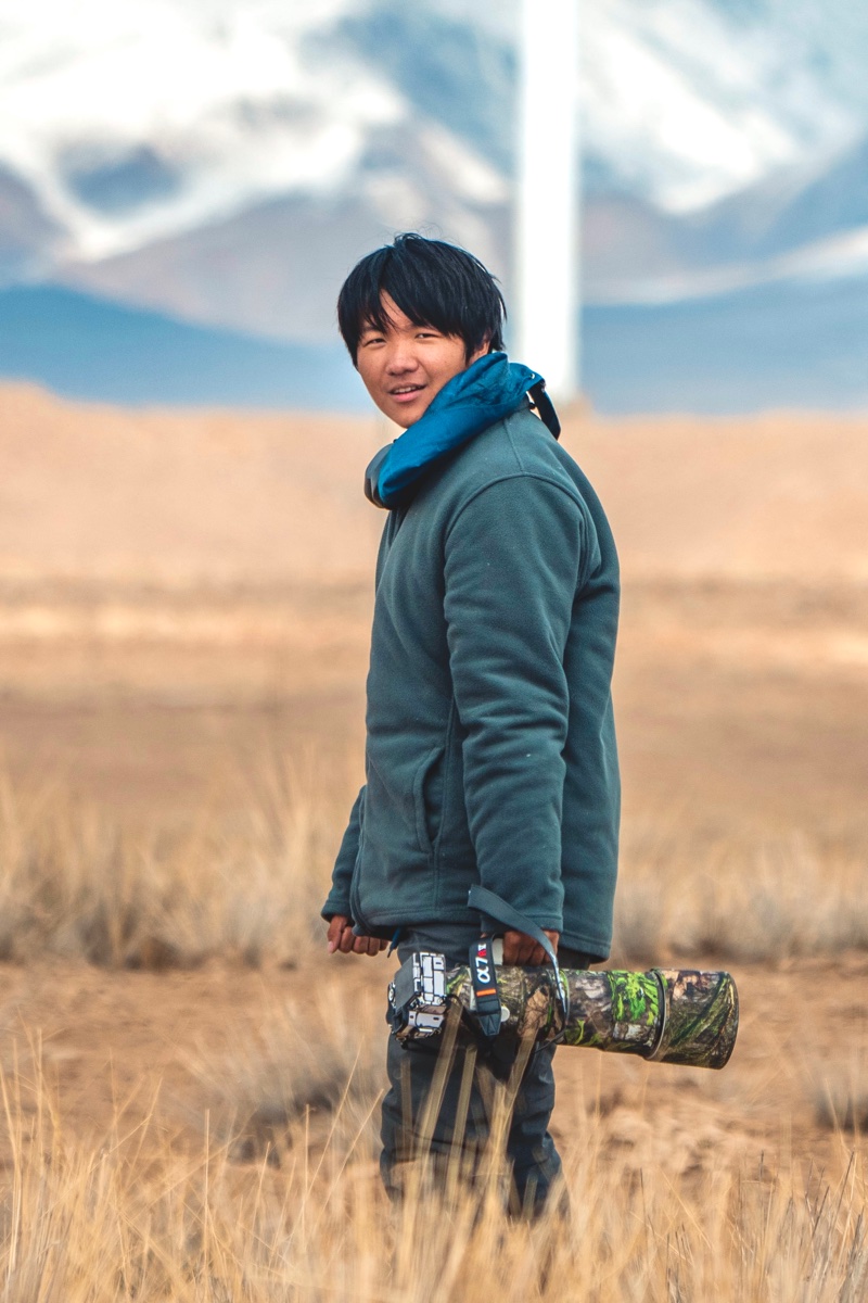YuanZhe Cui holding a camera in mountain grassland